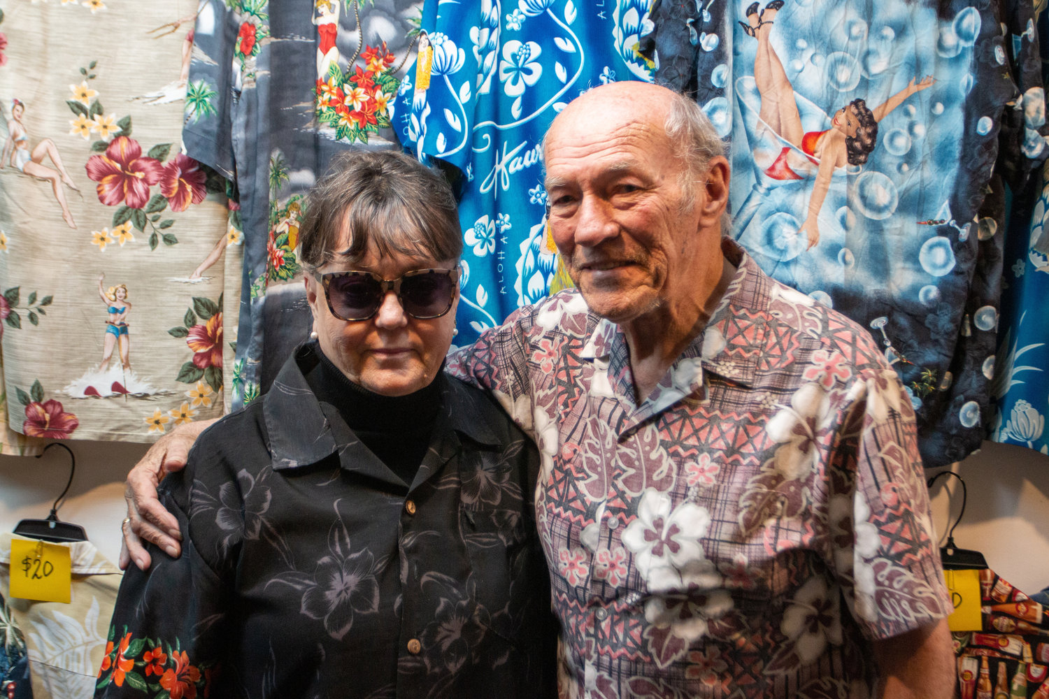 Pat and Phoebe Slusher pose together in front of a wall of Hawaiian shirts at their store, located at 107 N Tower Avenue. They have announced their retirement and plan to close their storefront in August.